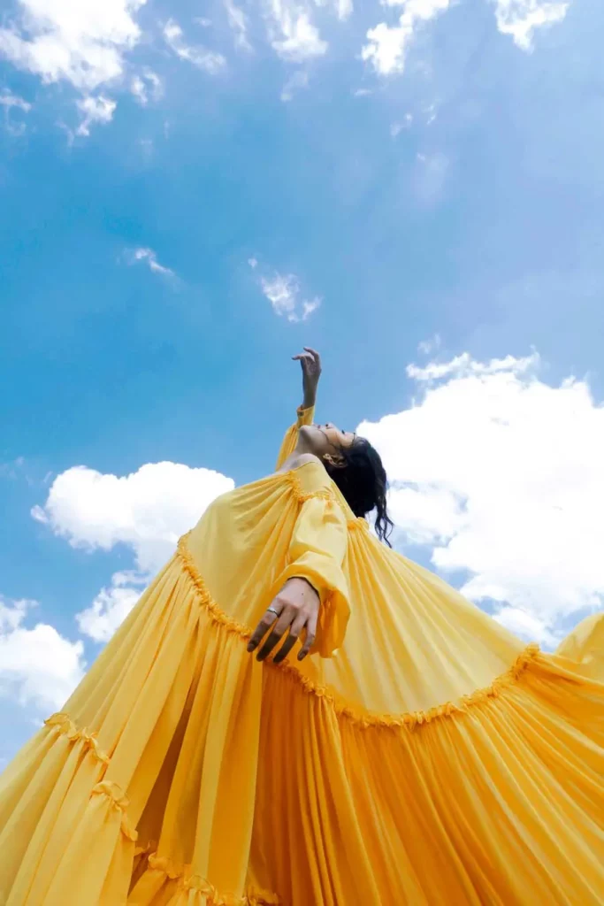 Werbeagentur Webdesign | Eine Frau hat ein gelbes Kleid. Sie hat ihre Augen zu und sie tanzt